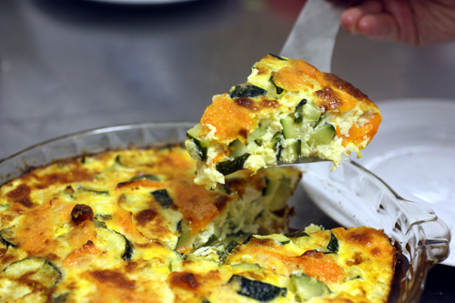 Lifting out a triangle shaped slice of Kusa Jibben, Syrian style quiche with zucchini and carrots
