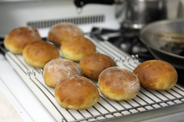 Nine freshly baked buns cooling on a rack
