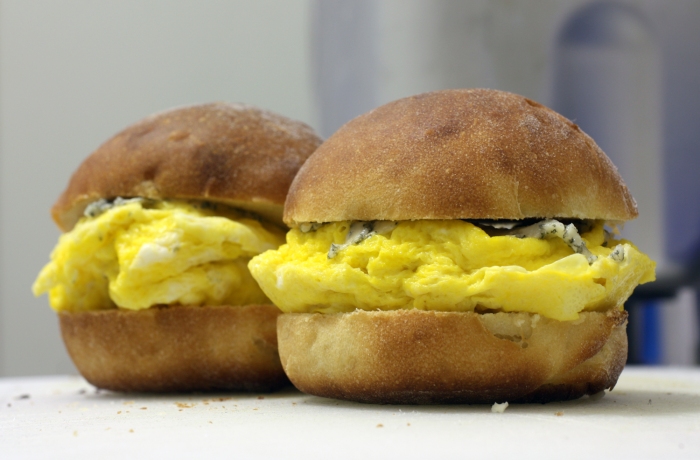 Two buns with egg and blue cheese sandwiched in the middle of each